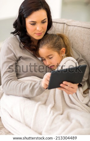 beautiful young woman using tablet computer while her daughter sleeping