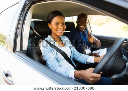happy young african woman taking driving lessons from instructor