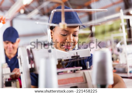 pretty african textile worker sewing with industrial sewing machine