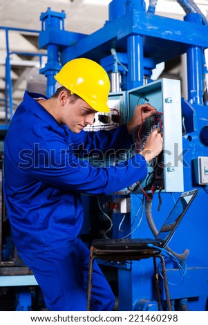 industrial technician repairing modern computerized machine in factory