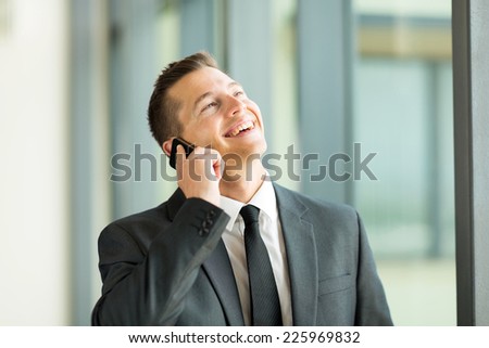 cheerful businessman talking on cell phone in office