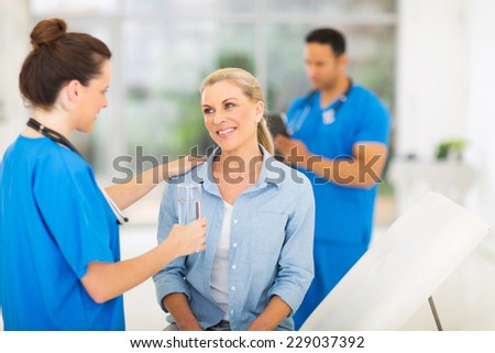friendly nurse giving patient glass of water in doctors office