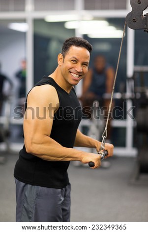muscular man using triceps pull down in gym