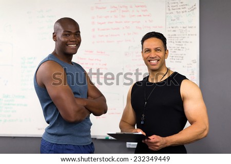 fitness trainer in gym with clipboard creating training plan for client