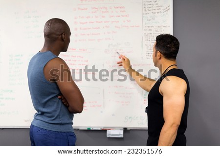 professional fitness coach planning gym session with client