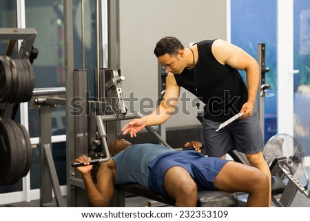athlete african man in gym with personal fitness trainer