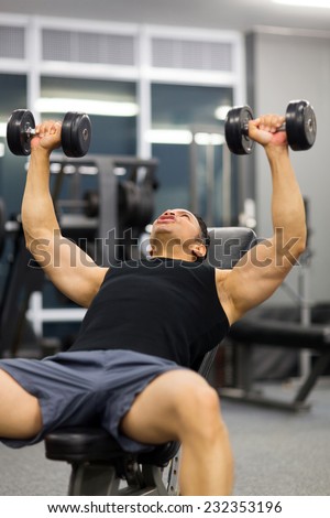 mid age man doing heavy weight exercise with dumbbells in gym