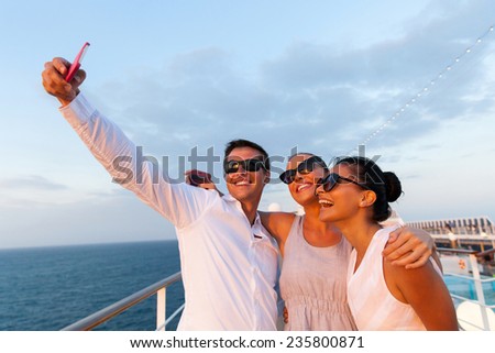 group of friends taking self portrait using smart phone on cruise
