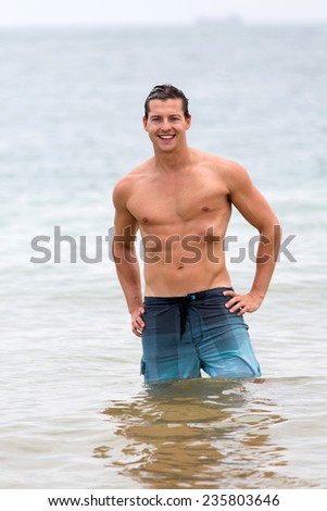 handsome man walking out of the water in tropical beach