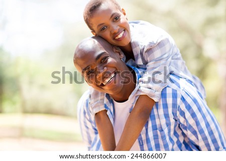 pretty african woman enjoying piggyback ride on boyfriend outdoors