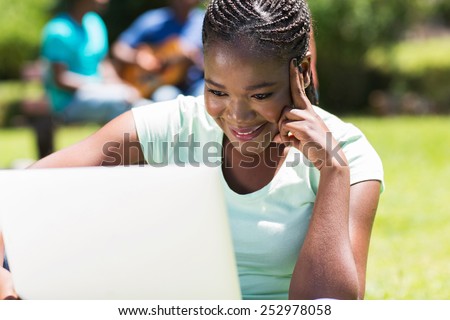 pretty female african college student working on laptop computer