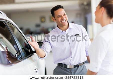friendly salesman selling car to a customer in showroom