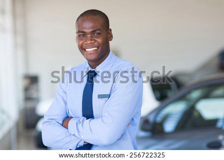 portrait of happy african car salesman in showroom