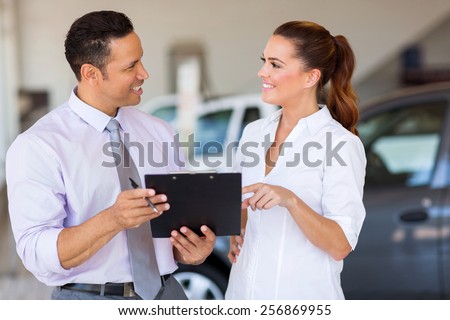 two happy car sales consultants working inside vehicle showroom