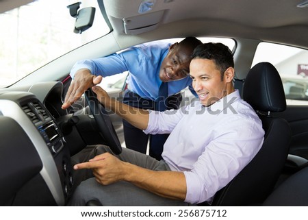 african car salesman showing new car interior to customer sitting inside the car