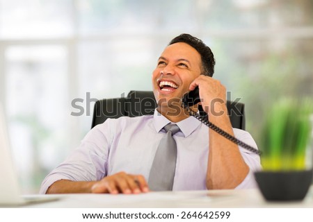 happy middle aged corporate worker talking on landline phone in office