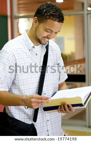 male college student reading a book in the passage