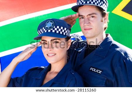 Two police officers saluting in front of south african flag