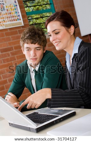 female teacher teaching high school boy computer