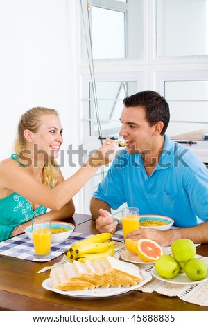 happy wife feeding breakfast to her husband