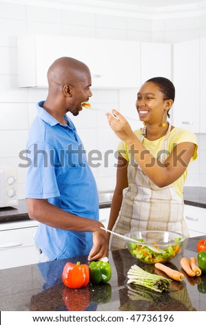 african couple tasting food in kitchen