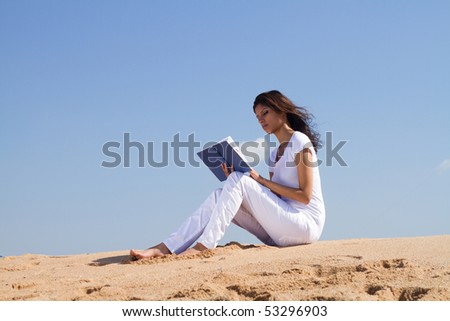 young beautiful happy arabic woman reading on beach