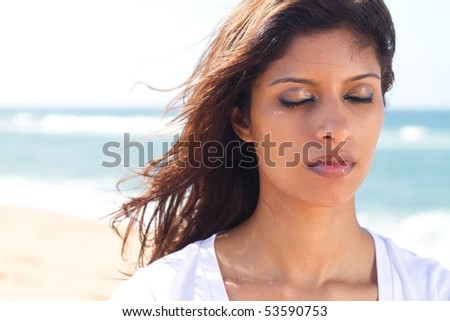 thoughtful young indian woman with eyes closed on beach