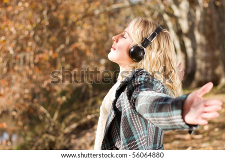 young woman listening music in autumn forest
