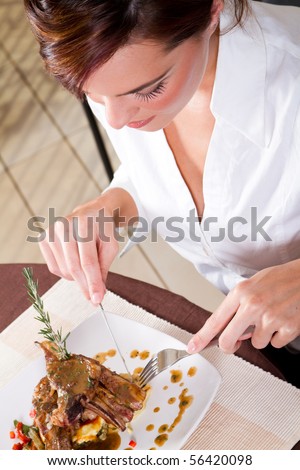 beautiful young woman eating steak in restaurant