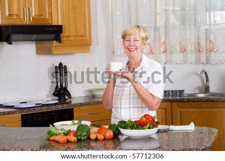 senior woman drinking tea or coffee in kitchen