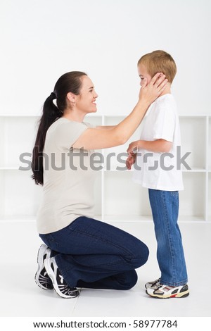 Mother kneeling down and comforting son against white background