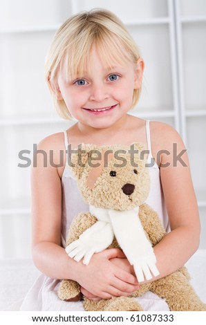 Little girl with band-aid on her face holding a teddy bear