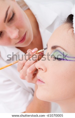 professional female makeup artist applying makeup to model\'s face