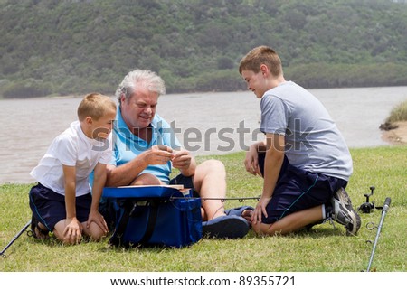 grandpa teaching grandsons how to put bait on fishing hook
