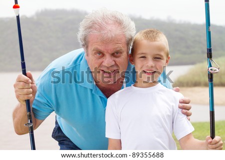 portrait of grandfather and grandson with fishing rods