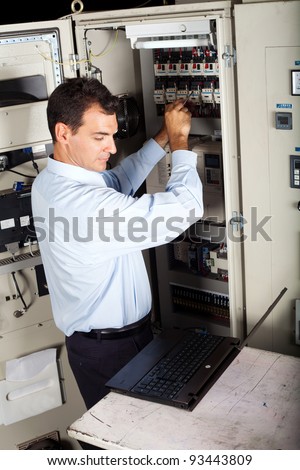 industrial technician repairing computerized machine with laptop computer