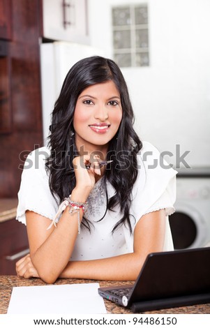 beautiful young indian woman doing home finance in kitchen