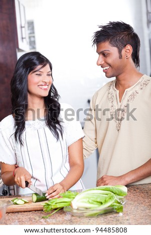 happy indian couple cooking in kitchen