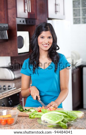 young indian woman cooking in kitchen