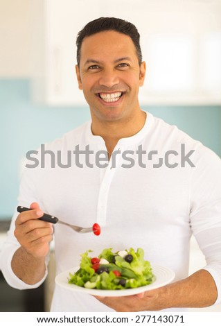 portrait of happy middle aged man eating green salad