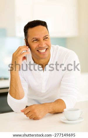 happy mid age man talking on cell phone at home