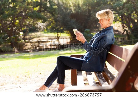 beautiful middle aged woman using smart phone outdoors