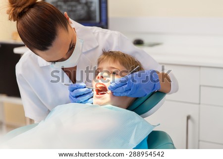 successful young dentist examining patient teeth