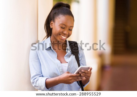 beautiful african university student texting on smart phone