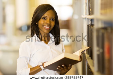 pretty female afro american university student reading book in library