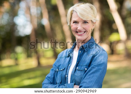 beautiful middle aged woman with arms folded outdoors