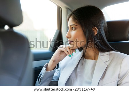 thoughtful indian business woman sitting in car backseat