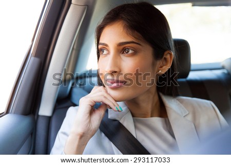 pretty indian business executive daydreaming in a car