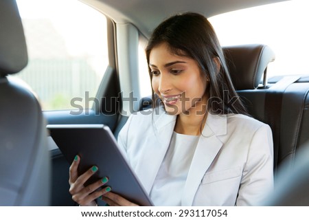 happy indian businesswoman using tablet computer inside a car