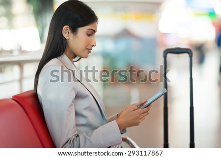 indian businesswoman using tablet computer while waiting for her flight at airport